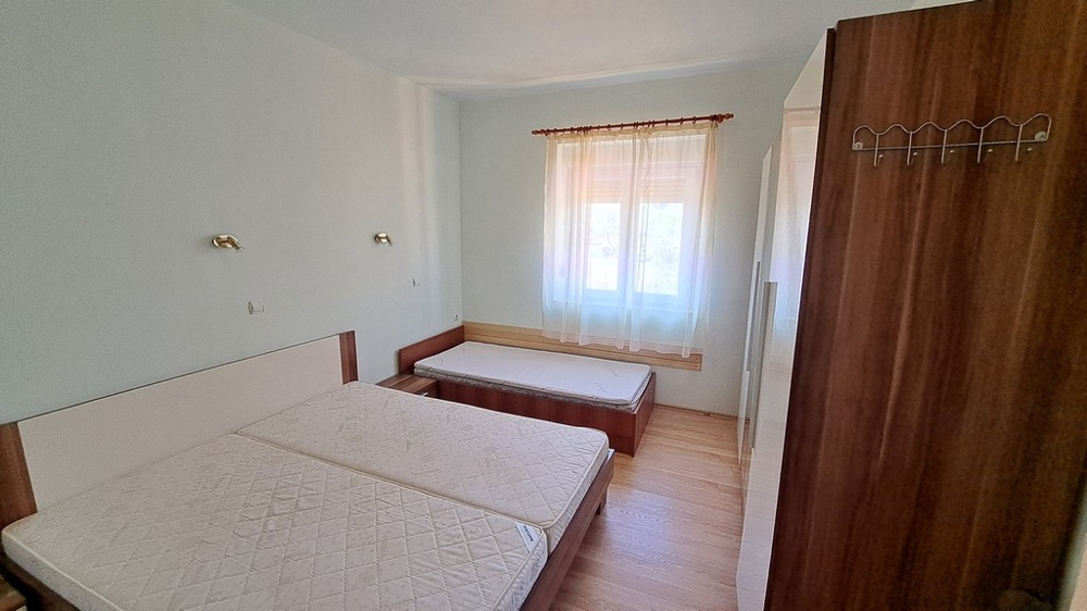 Ljust sovrum med två bäddar, inuti en del av en strandfastighet i Kroatien