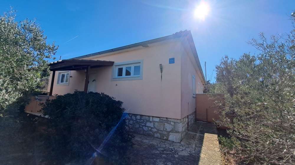 Utsikt över sidan av ett hus omgivet av medelhavsväxter, kustfastighet i Kroatien