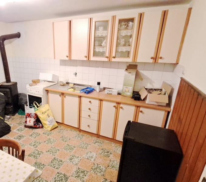 Enkelt kök med träskåp och vitt kakel i ett hus till salu på ön Pasman i Kroatien.