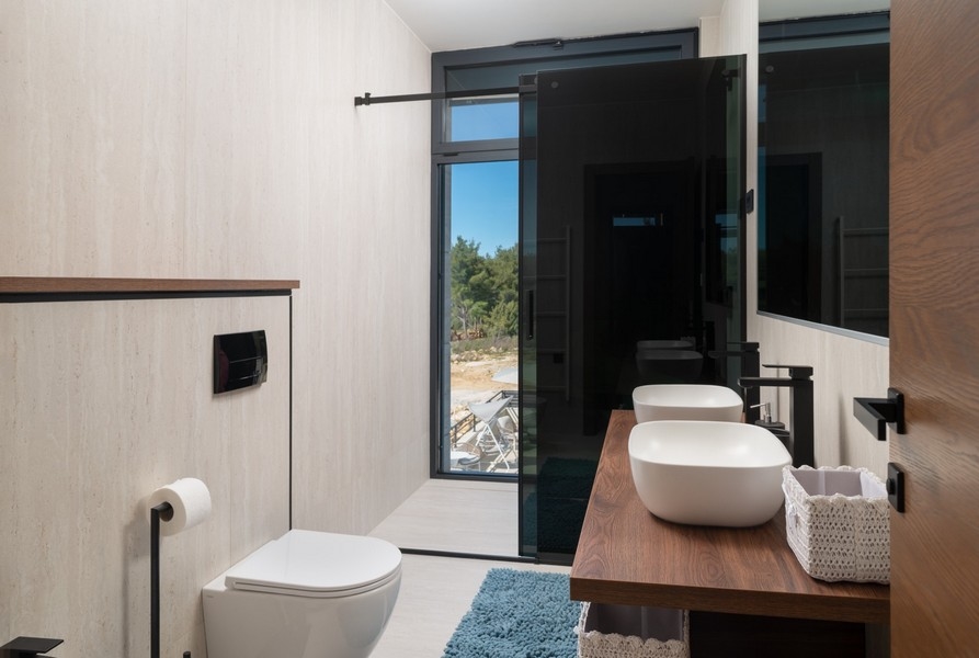 Snyggt badrum med havsutsikt i en försäljningsvilla i Razanac, Zadar-regionen, Kroatien, utrustat med en vägghängd toalett och ett modernt tvättställ på ett underskåp i trä.