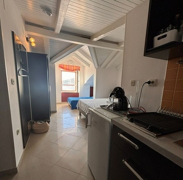 Kompakt pentry med intilliggande sovplats i en kroatisk fastighet. 4 matbord med utsikt över en marina scen genom fönstret på en fastighet i Kroatien