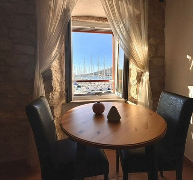 Rum med sluttande tak och utsikt över hamnen genom ett fönster i en fastighet i Kroatien