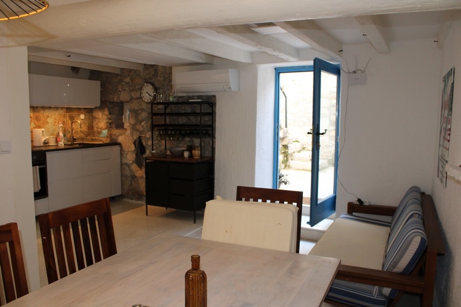 Interiörvy av stenhus i Murter, vardagsrum och matplats.