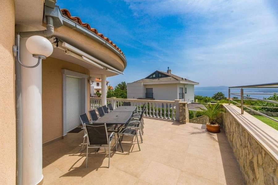 Stor terrass i ett hyreshus i Kroatien med ett långt bord och stolar, havsutsikt