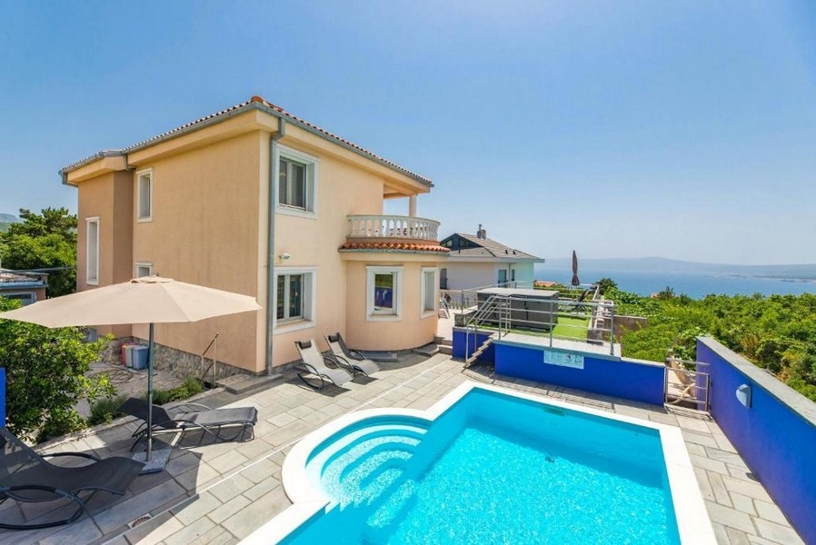 Bakgård till ett hyreshus i Kroatien med pool och solstolar, havsutsikt