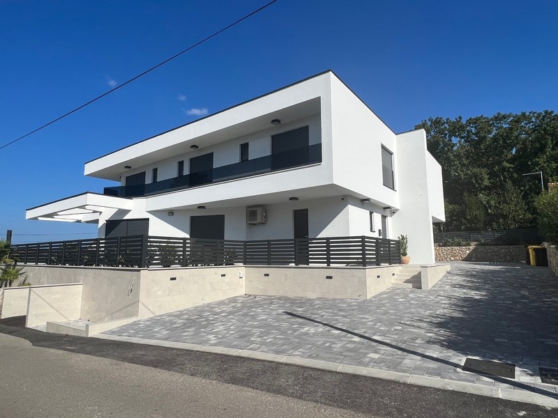 Utsikt över en fastighet i Kroatien: Vitt parhus med stora fönster och yttre betongtrappa i Njivice.