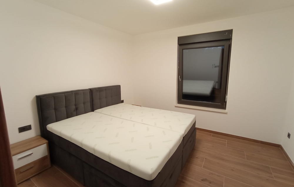 Liknande perspektiv på sovrummet i en fastighet i Kroatien, med ett sängbord och ett stängt fönster.