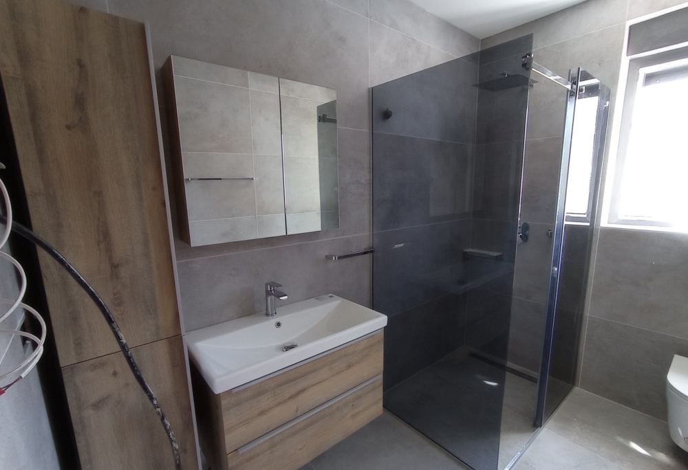 Modernt badrum med duschkabin i fastighet i Kroatien, spegelskåp och träelement i designen.
