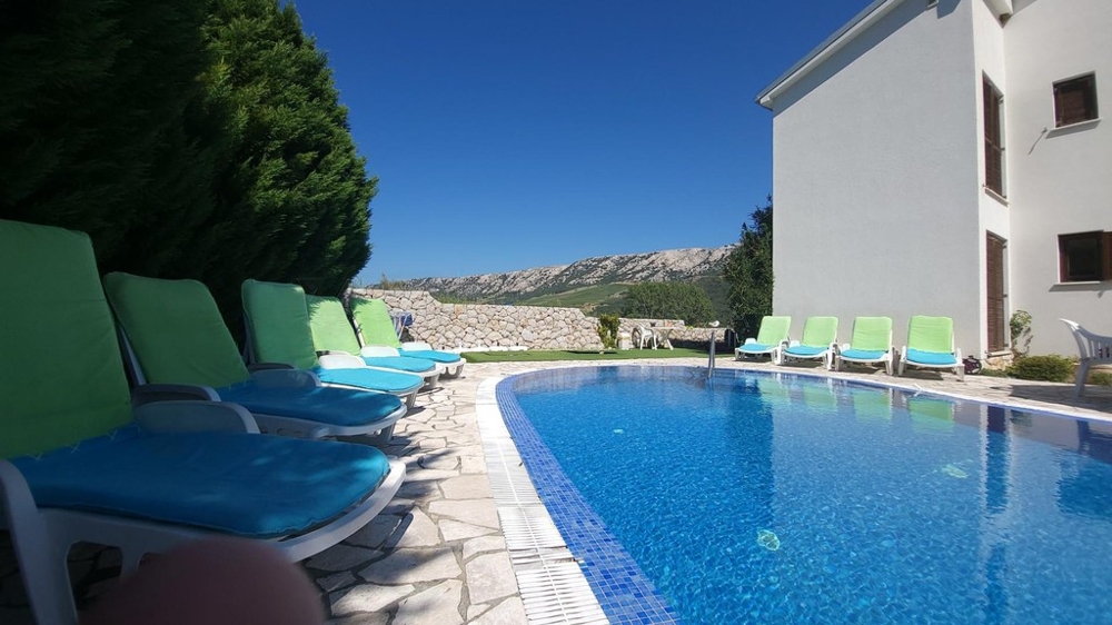 Pool med solstolar bredvid huset