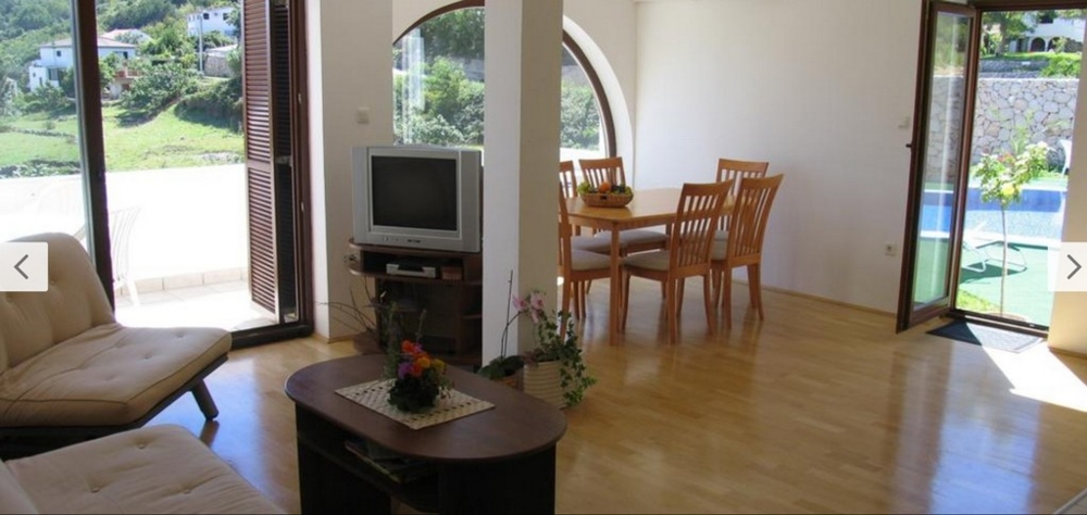 Interiörvy av ett ljust vardagsrum med trägolv och tillgång till poolen, fastigheter Kroatien