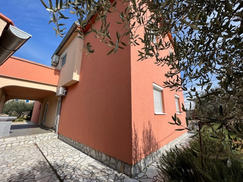 Fastigheter Kroatien, staden Krk, ön Krk Köpa ett hyreshus, närbild av sidan av huset med fönster och olivträd i förgrunden