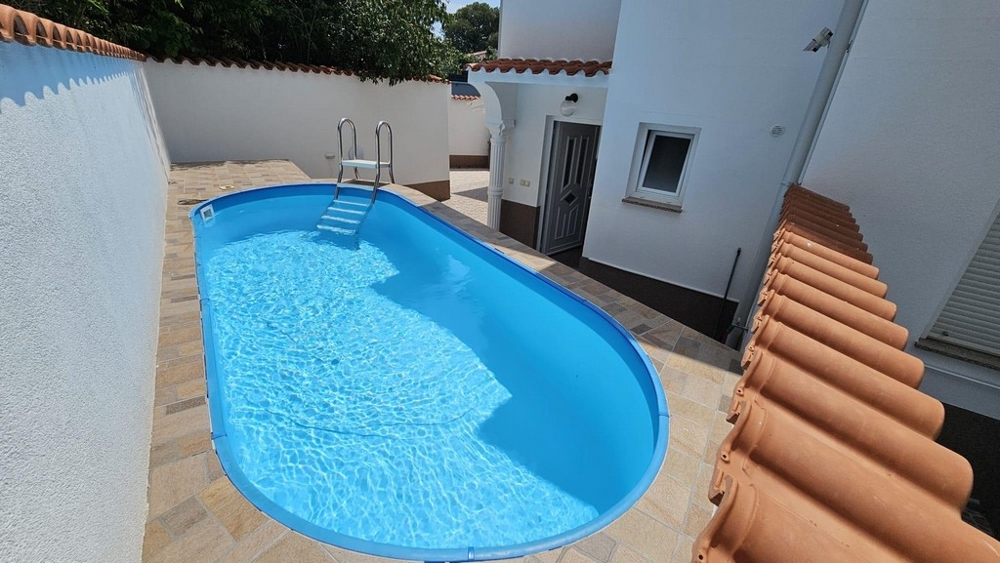 Exteriör vy av gult parhus med balkonger och trappor i en grön trädgård