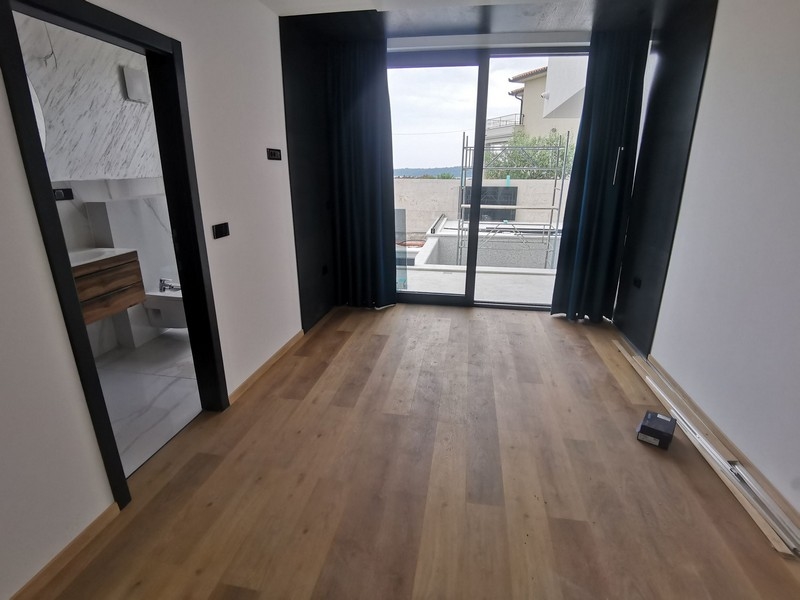 Interiörvy av ett sovrum med trägolv och ett stort fönster