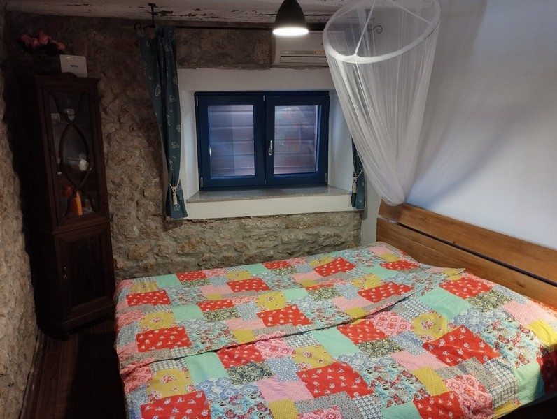 Mysigt sovrum med färgglatt täcke, perfekt för alla som vill köpa ett hus i Kroatien.