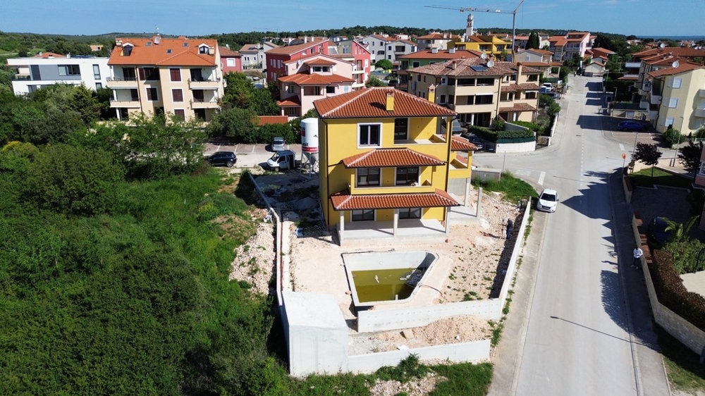 Rymlig villa i Kroatien under byggskedet, omgiven av moderna hus och grönområden