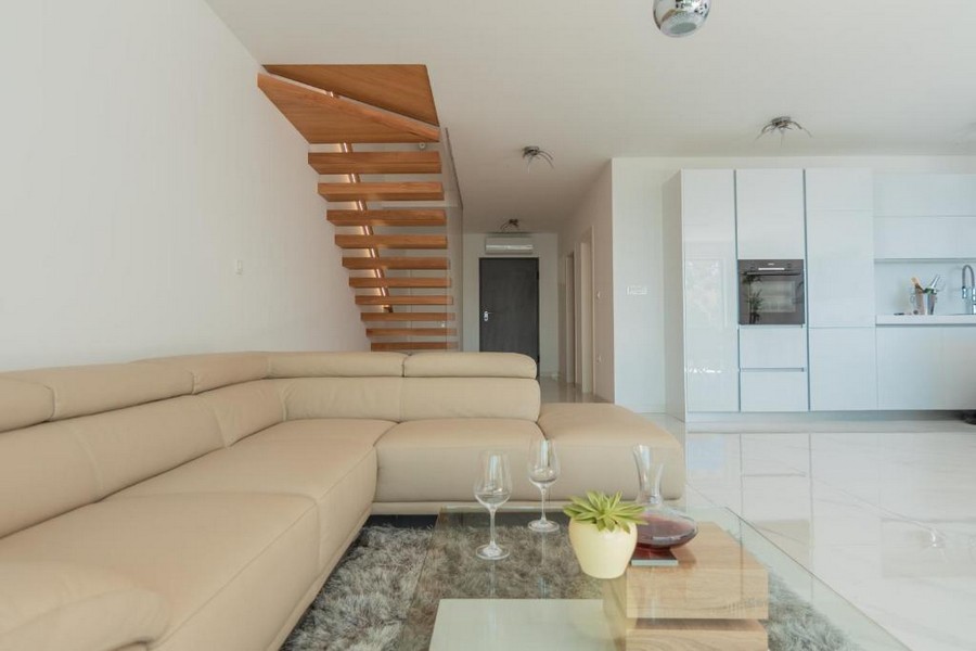 Stilrent vardagsrum med öppet kök och trappa