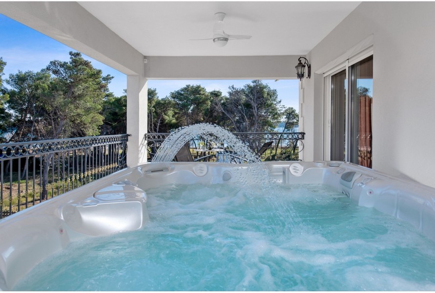 Jacuzzi på terrassen på Villa H3042 med utsikt över havet och trädgården