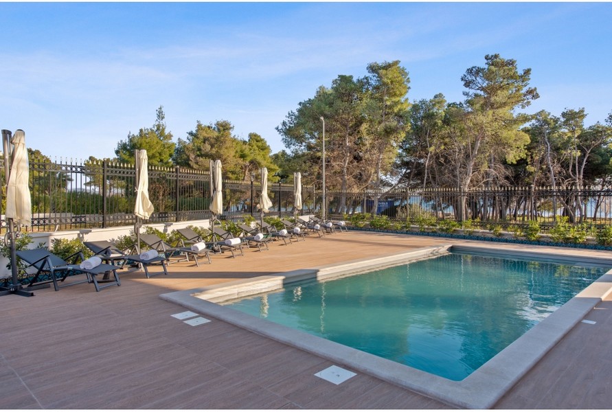 Uteområde i Villa H3042 med en uppvärmd utomhuspool och solstolar omgiven av medelhavsväxter