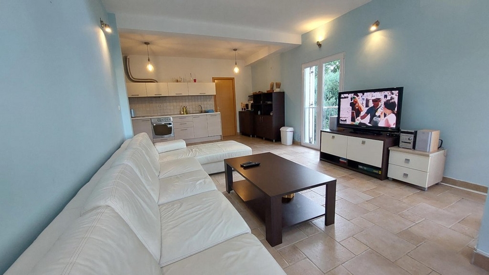 Vardagsrum med vit soffa, soffbord och TV i ett hus i Kroatien