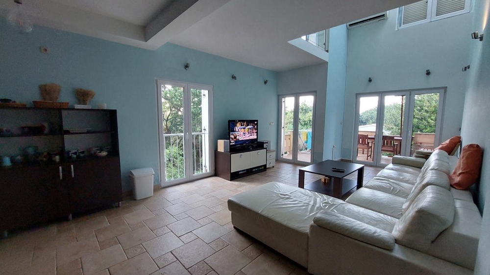 Rymligt vardagsrum med vit soffa, TV och matplats i ett hus i Kroatien