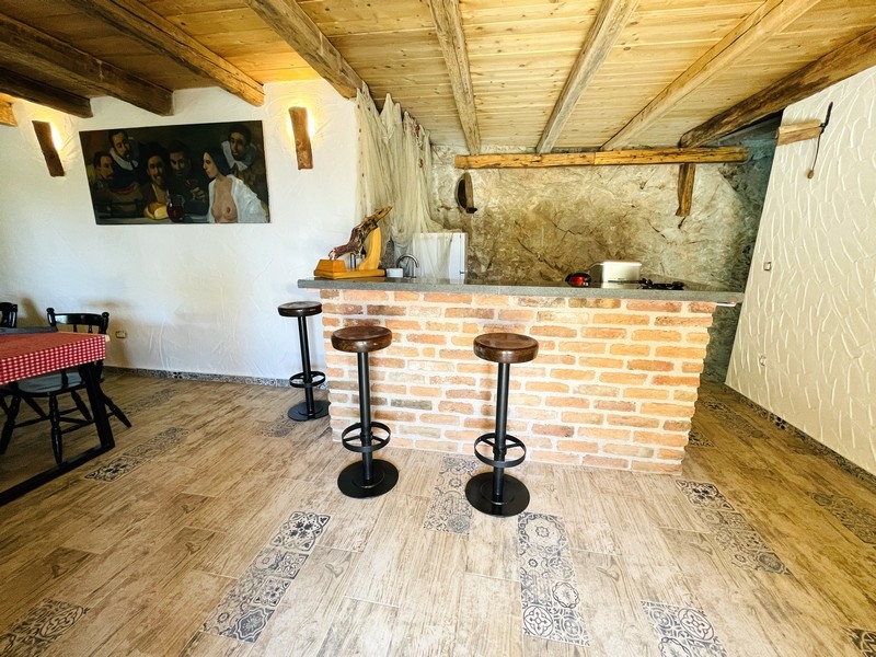 Rustik krog med våtbar i tegel, takbjälkar och barstolar