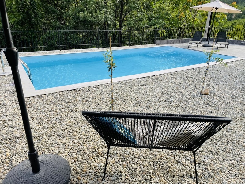 Pool i trädgården, omgiven av småsten, med utsikt över skogen