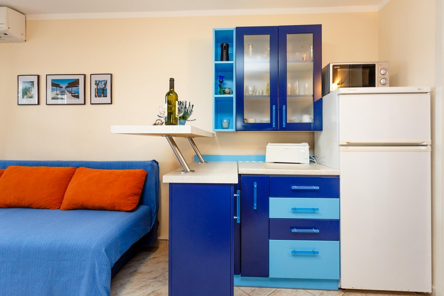 Kök med blå skåp, vitt kylskåp och små köksredskap