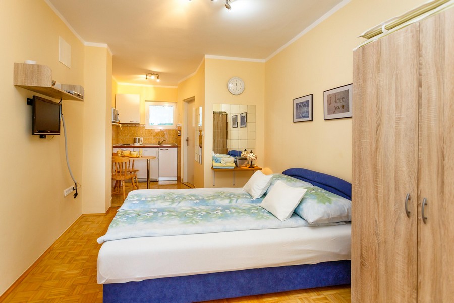 Studiolägenhet med dubbelsäng, litet matbord och köksdel