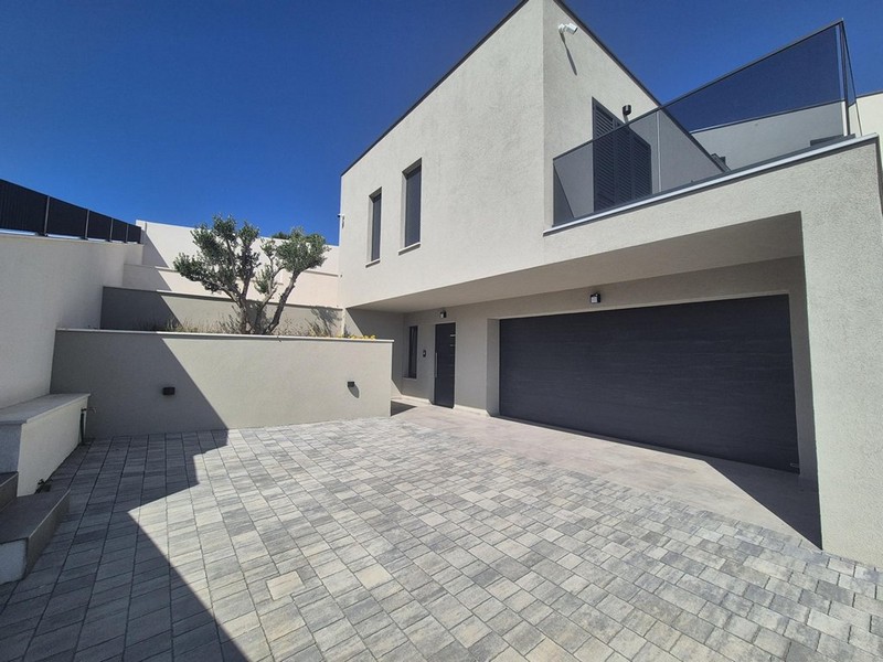 Utsikt från terrassen över havet och omgivande hus, modern byggnad med pelare och glasräcken