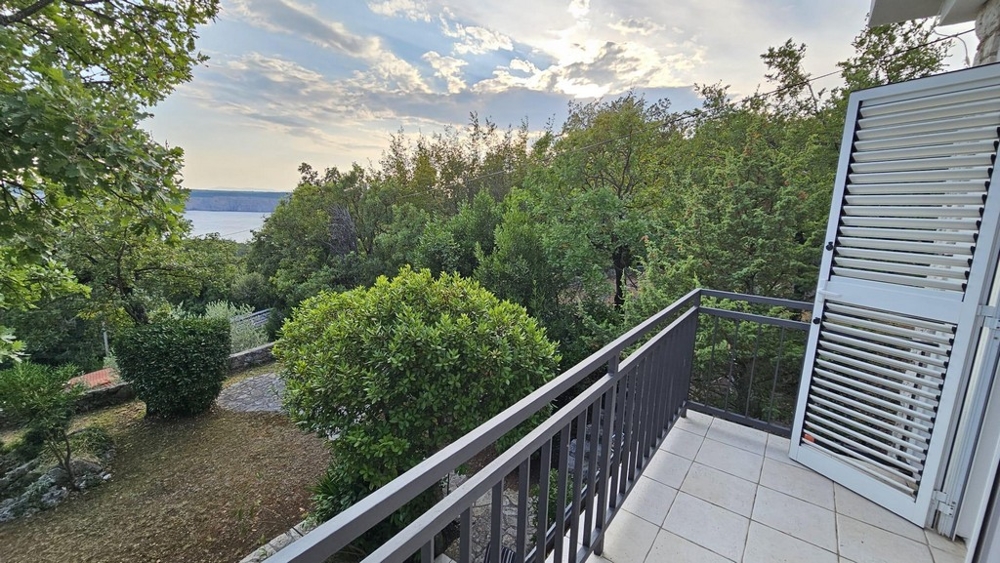 Balkong med utsikt över träd och havet i bakgrunden
