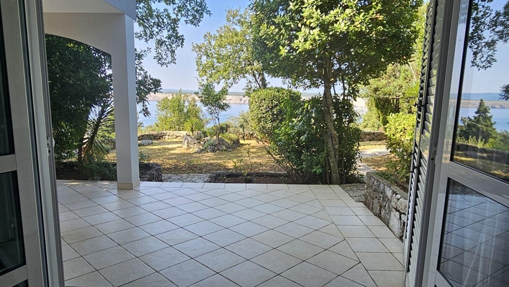 Terrass på bottenvåningen med utsikt över trädgården och havet