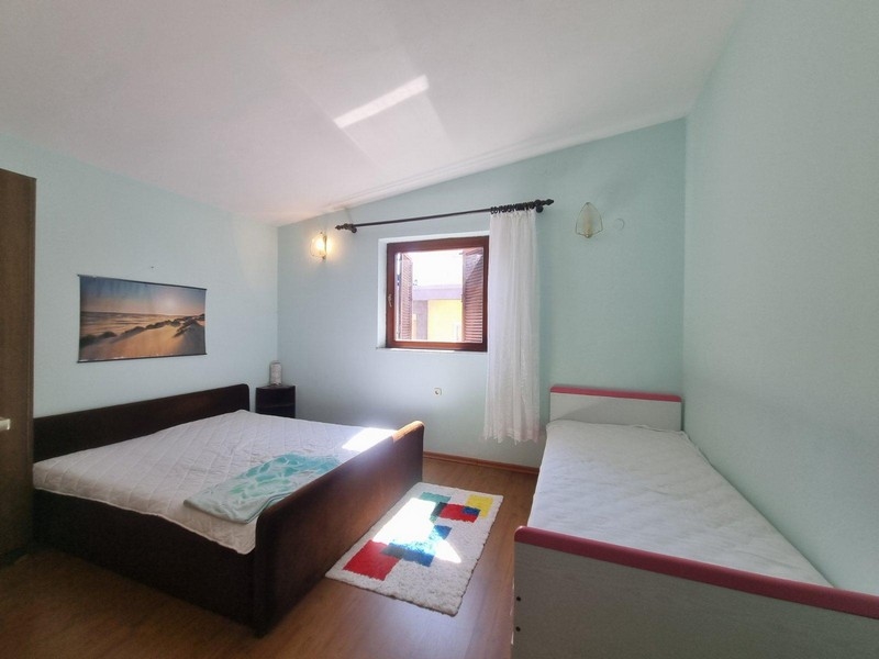 Sovrum med dubbelsäng och enkelsäng, ljusa väggar och fönster med naturligt ljusinsläpp.