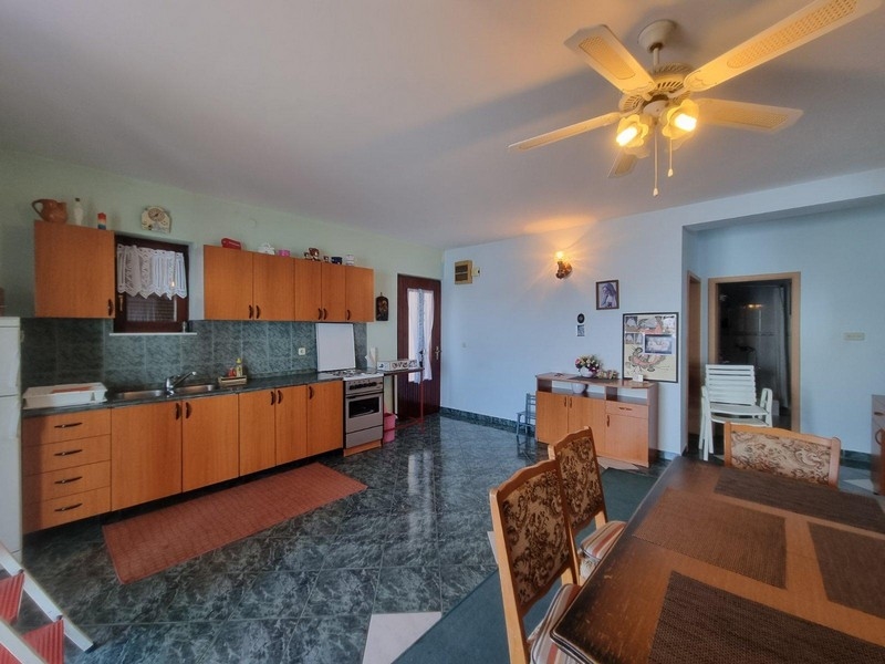 Rymligt kök med matbord, trämöbler och takfläkt i en ljus miljö.