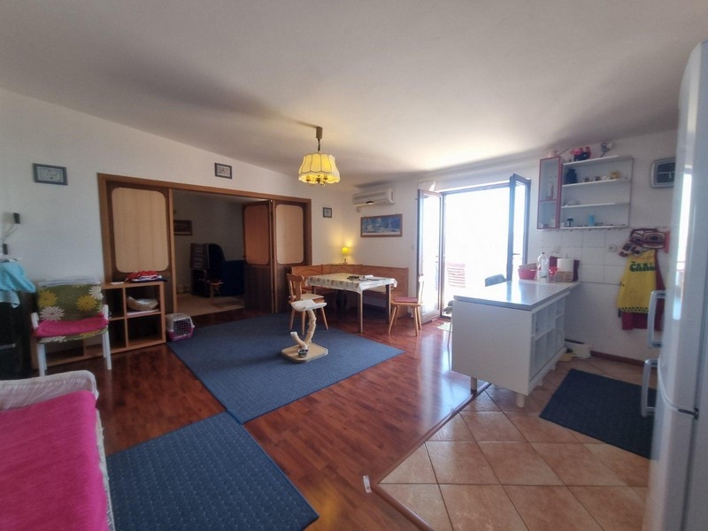 Öppet vardagsrum med trägolv och direkt tillgång till terrassen, bekväma sittplatser och matplatser.