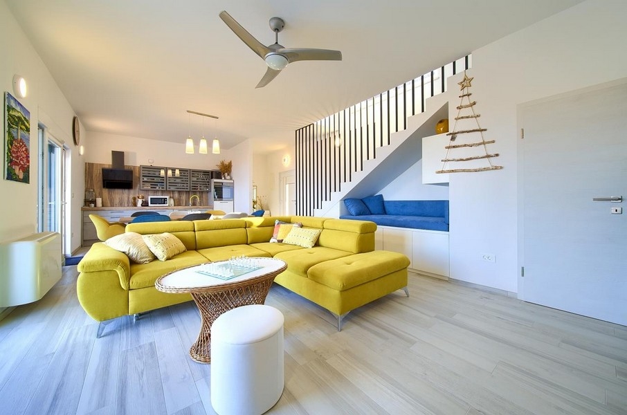 Stort vardagsrum med gul soffa, integrerad mat- och köksdel, öppen modern design