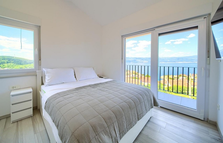 Sovrum med dubbelsäng och balkongdörrar, underbar havsutsikt i bakgrunden