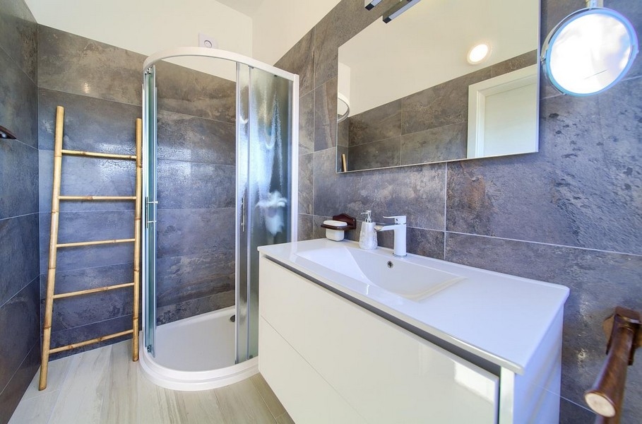 Modernt badrum med dusch, grått väggkakel och vitt underdel