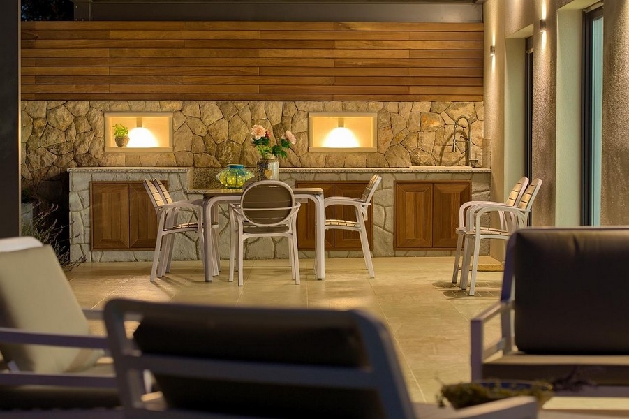 Täckt uteservering med stenpentry och träskåp, stilfullt upplyst