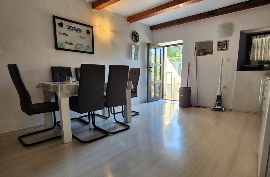 Ljus matsal med modern inredning och träbjälkar.