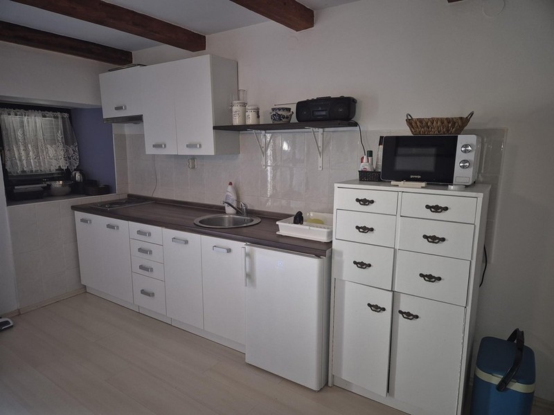 Modernt vitt kök med små skåp och hyllor.