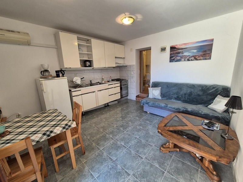 Öppet vardagsrum med kök, matbord och soffa, utrustat med klinkergolv.