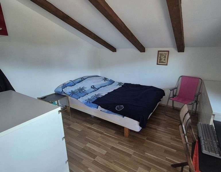 Sovrum på vinden med träbjälkar och dubbelsäng.