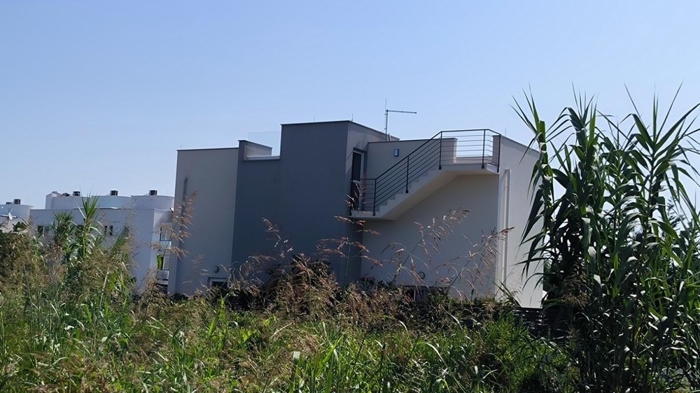 Vy bakifrån av huset med terrass och trappa till övervåningen.