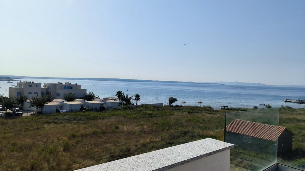 Havsutsikt från terrassen med intilliggande hus och natur.