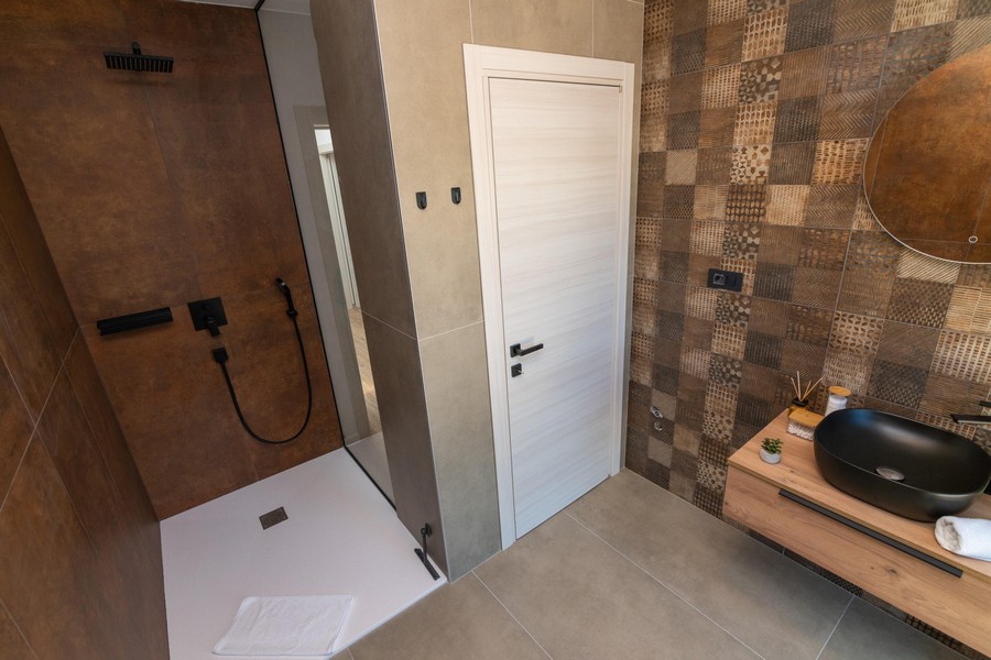 Modernt badrum med öppen dusch och stilrent kakel