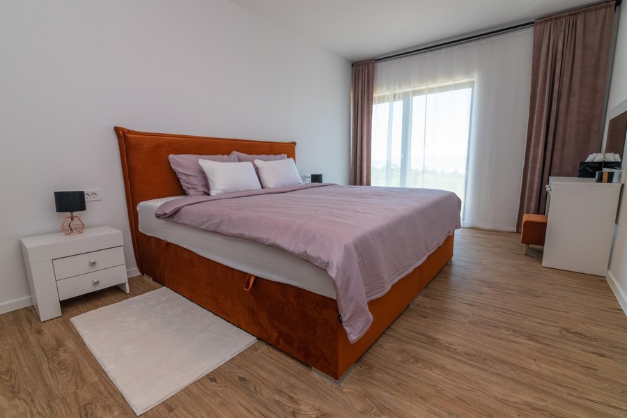 Sovrum med orange säng och stora fönster
