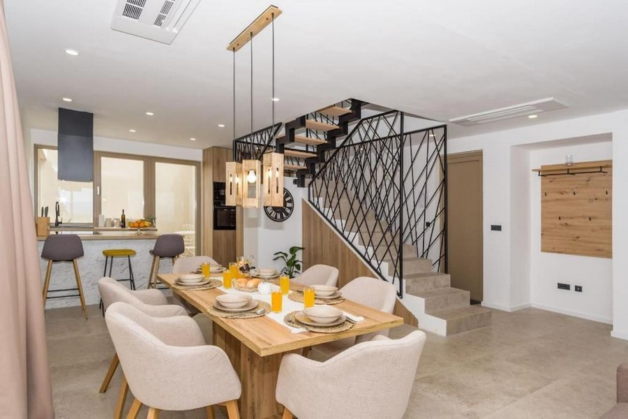 Utsikt över matbordet och köket samt villans moderna trappa.