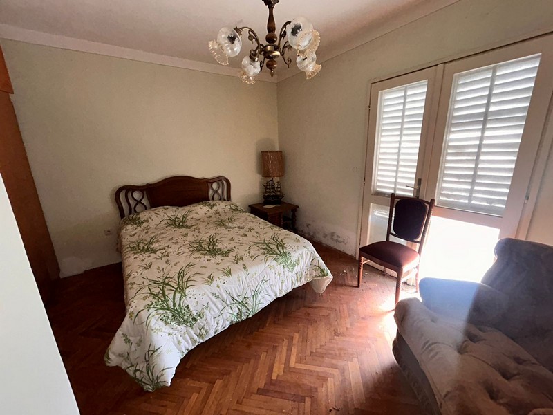 Sovrum med dubbelsäng, ljust fönster och gamla möbler