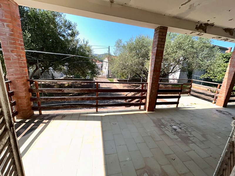 Täckt terrass med utsikt över trädgården och havet