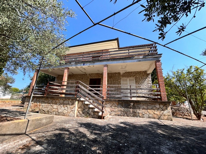 Exteriör vy av huset med stor terrass och olivträd